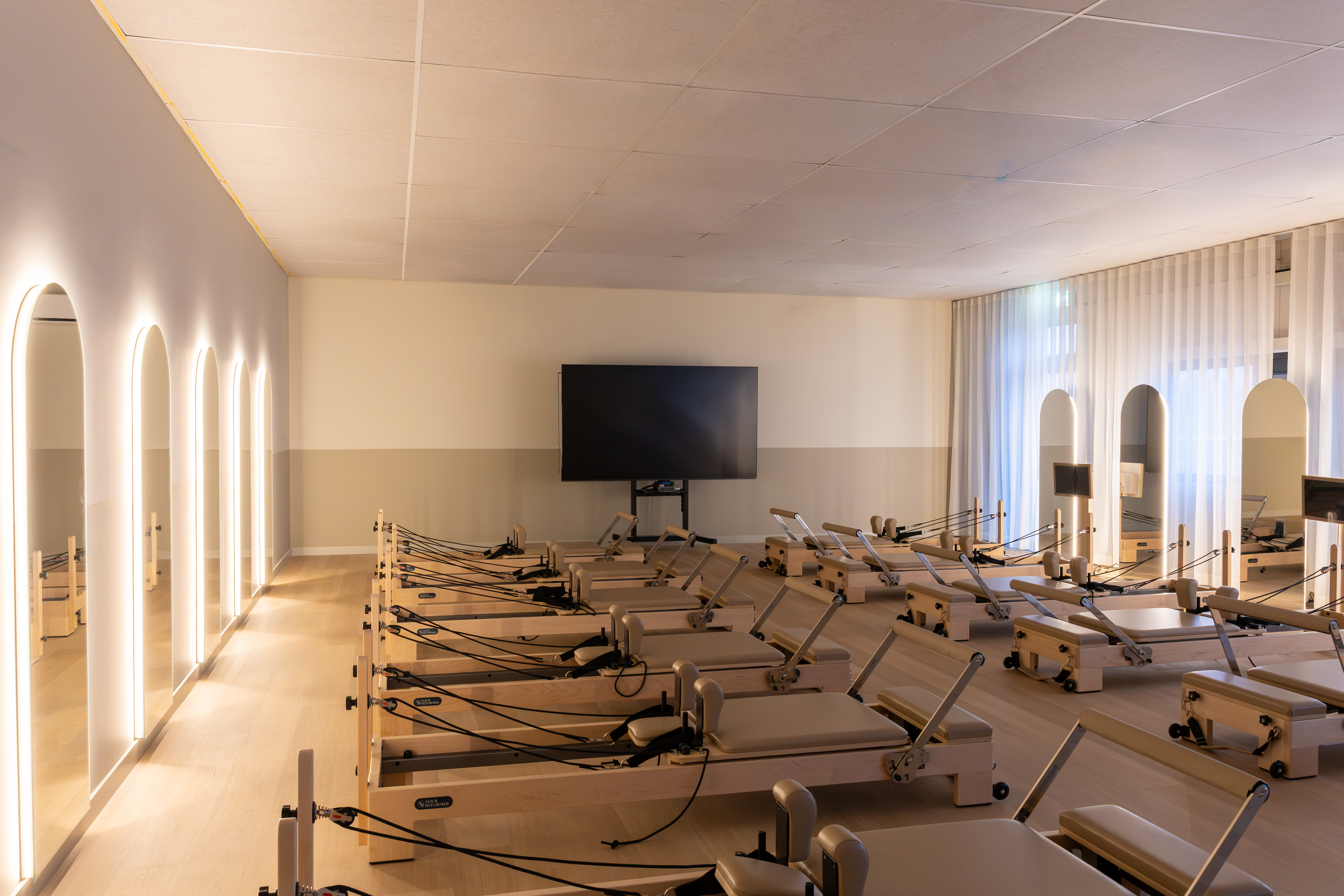 Reformer-studio met lichtgevende boogspiegels en tv-scherm
