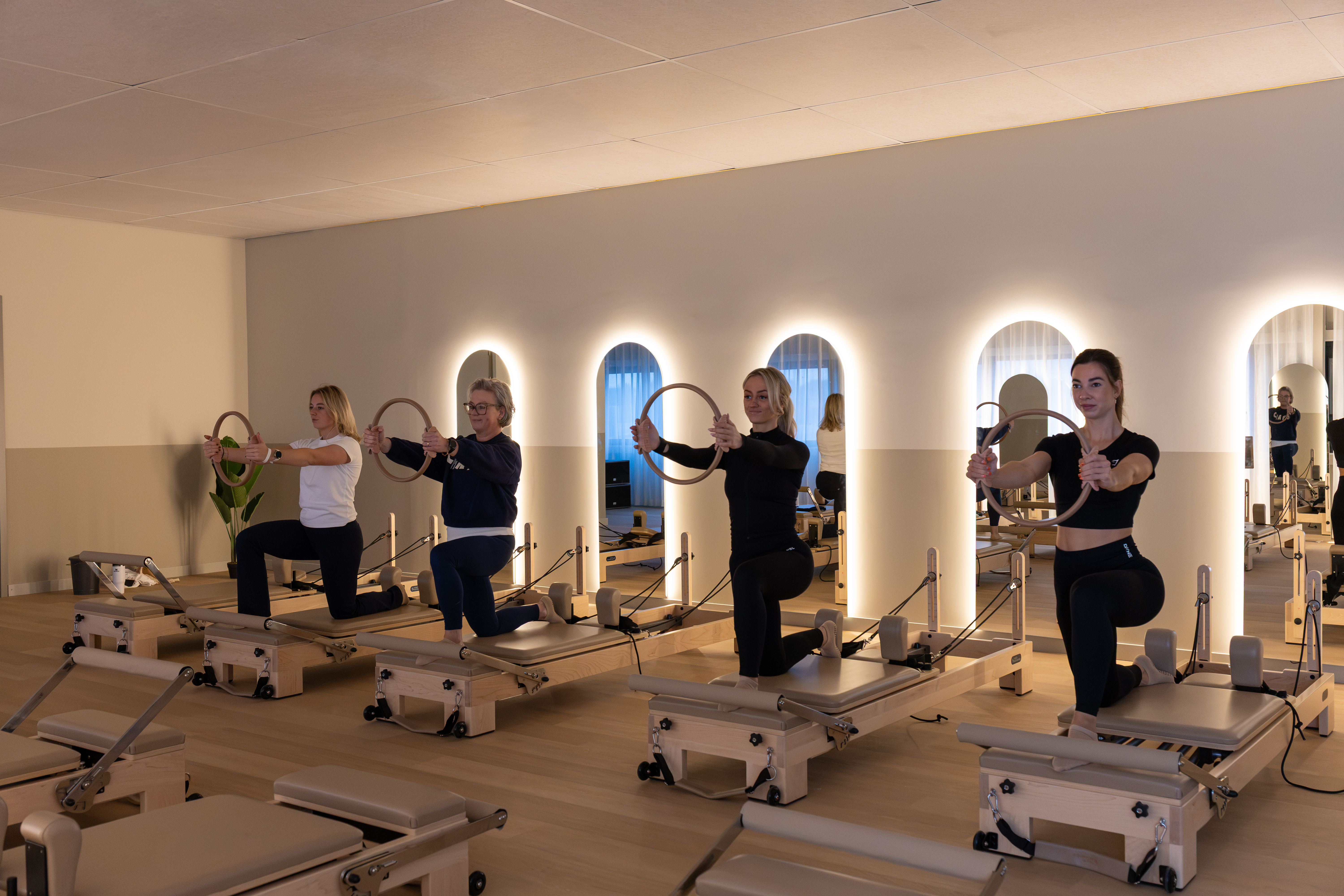 Deelneemsters oefenen met de pilates ring op de reformer in de studio