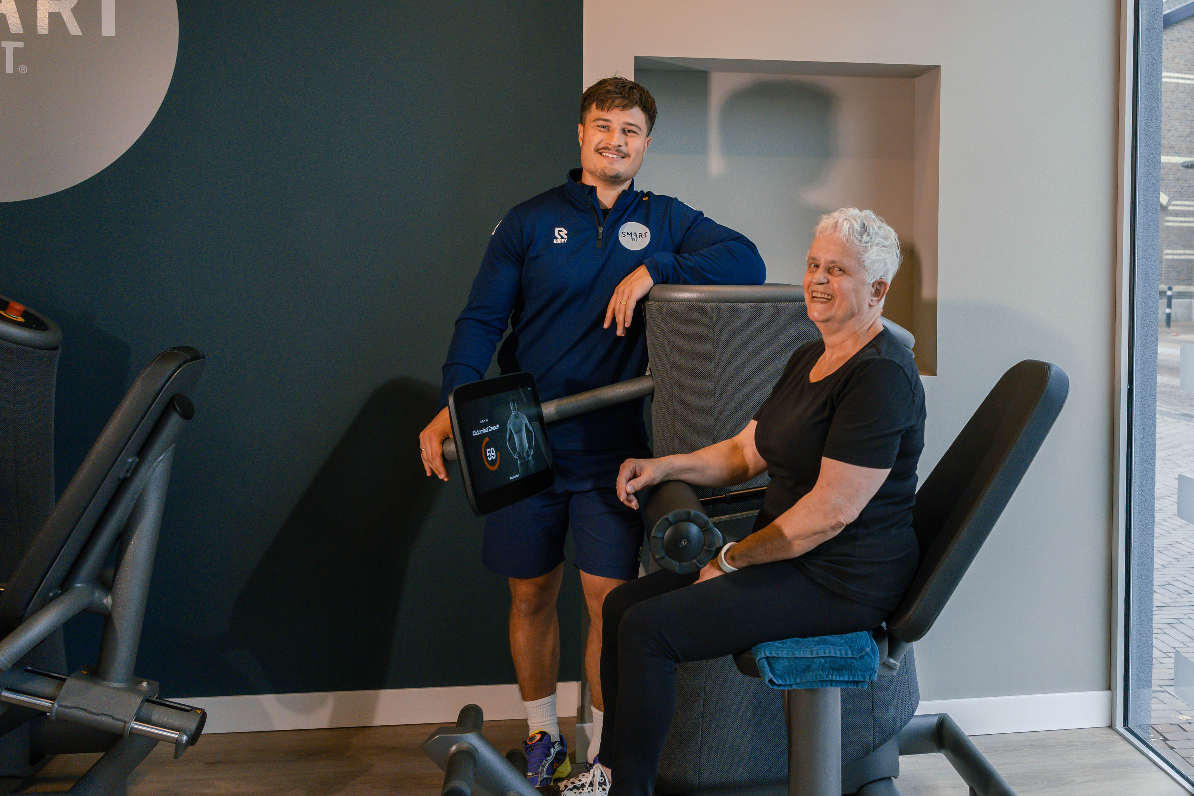 Trainer begeleidt een lid op de EGYM bij Smart Fit Nederweert